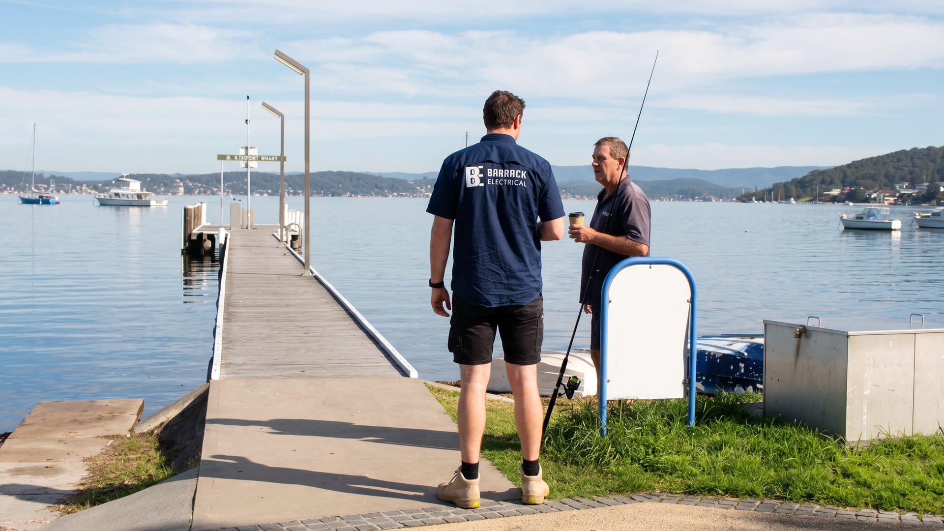 A Barrack Electrical electrician talking with a fisherman on Belmont Wharf at Lake Macquarie