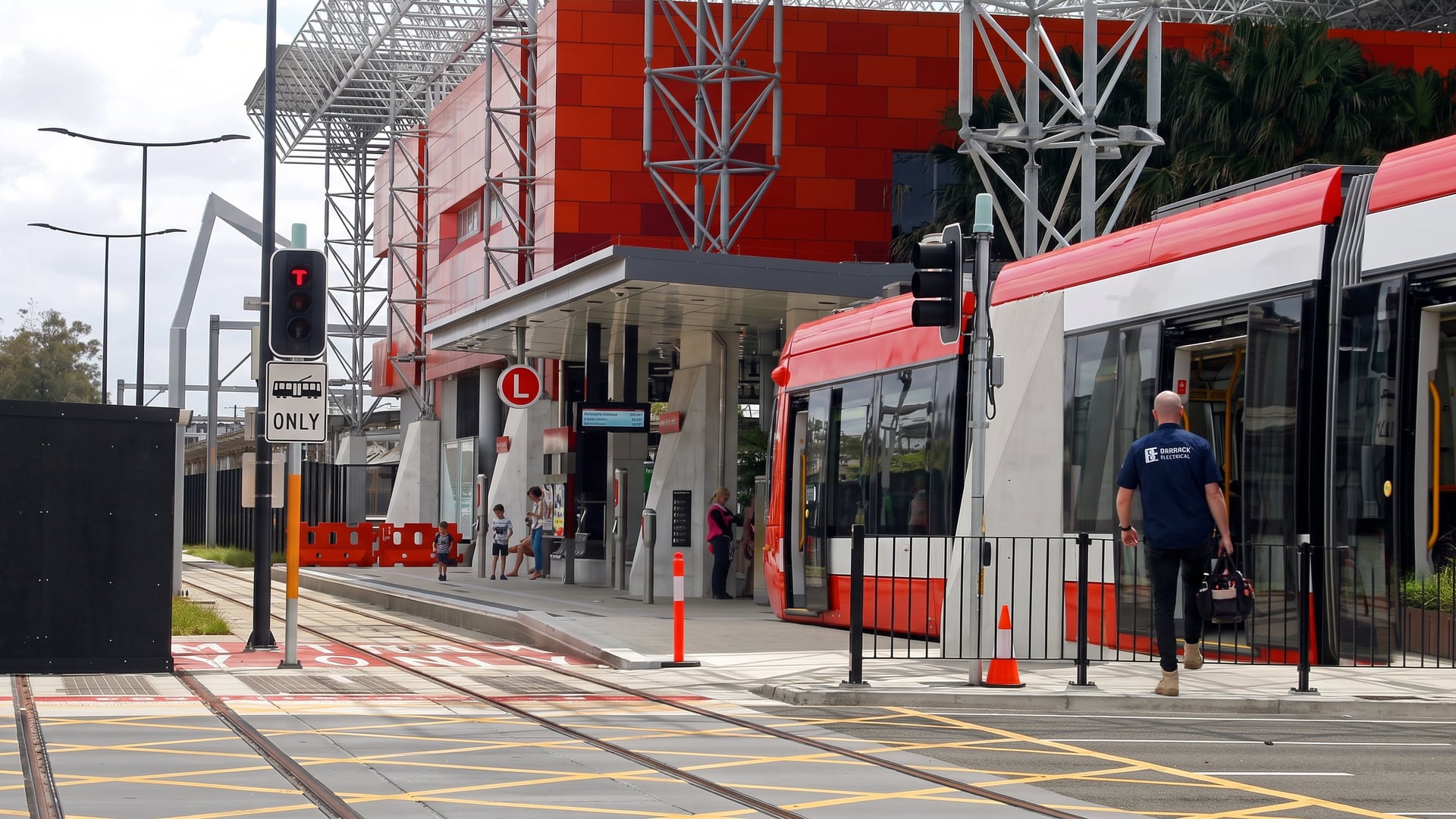 A Barrack Electrical electrician stepping aboard a light rail tram at Newcastle Interchange, Wickham