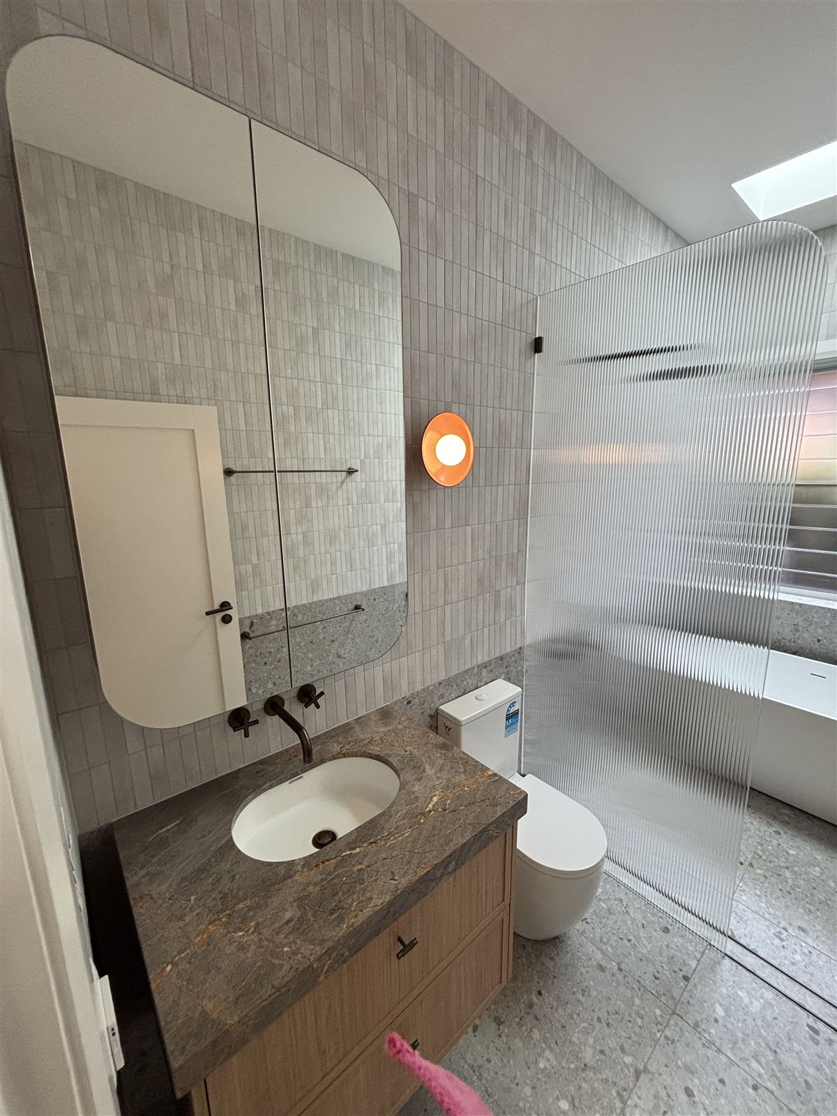 A round wall light beside a bathroom mirror