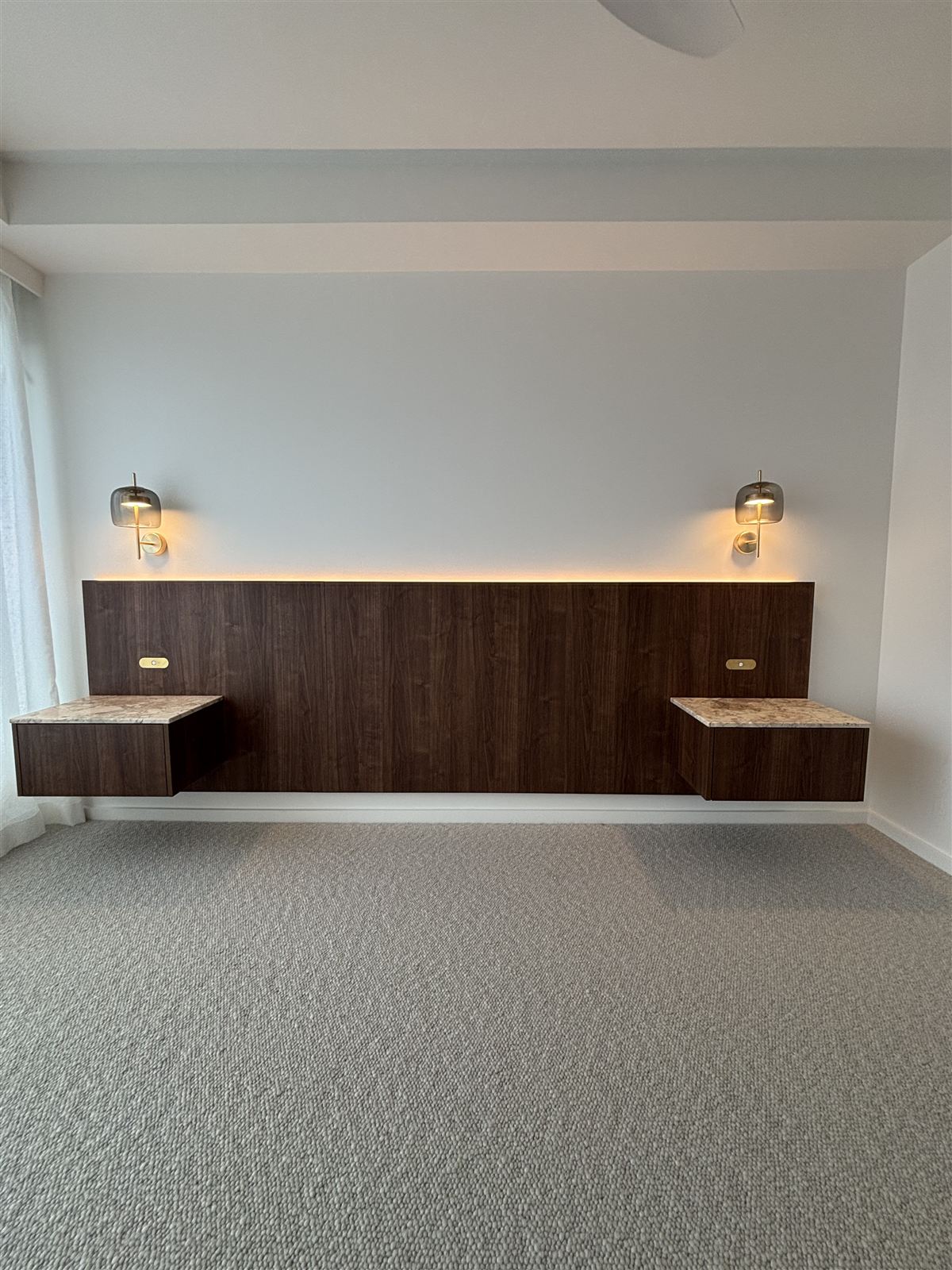 Bedroom bedhead with glass wall lights and warm LED strip lighting behind it