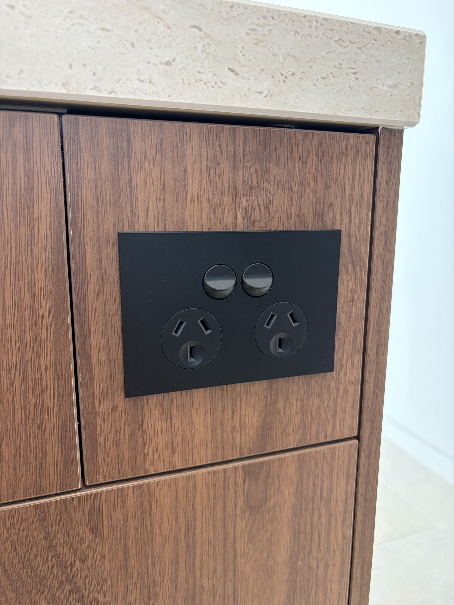 A matte black double power point fitted flush into the timber end of a kitchen island
