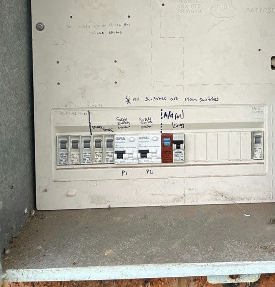 A switchboard with two safety switches among the breakers, the circuits noted by hand on the cover