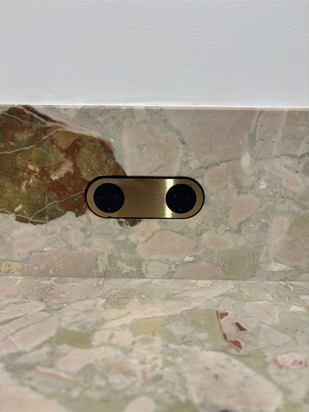 A brass power point fitted into a stone splashback