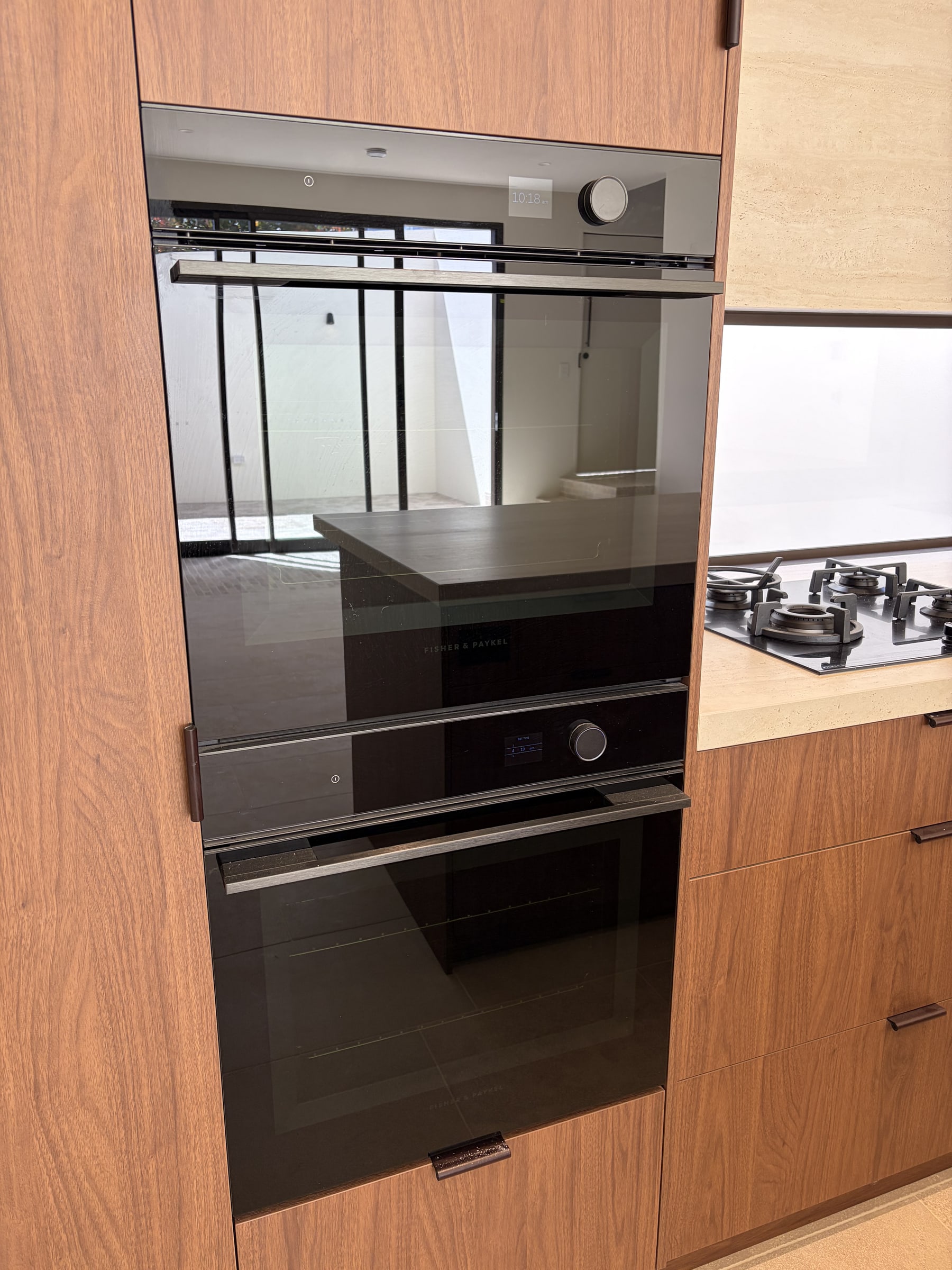 A built-in double wall oven installed in a timber cabinet, with a gas cooktop on the bench alongside