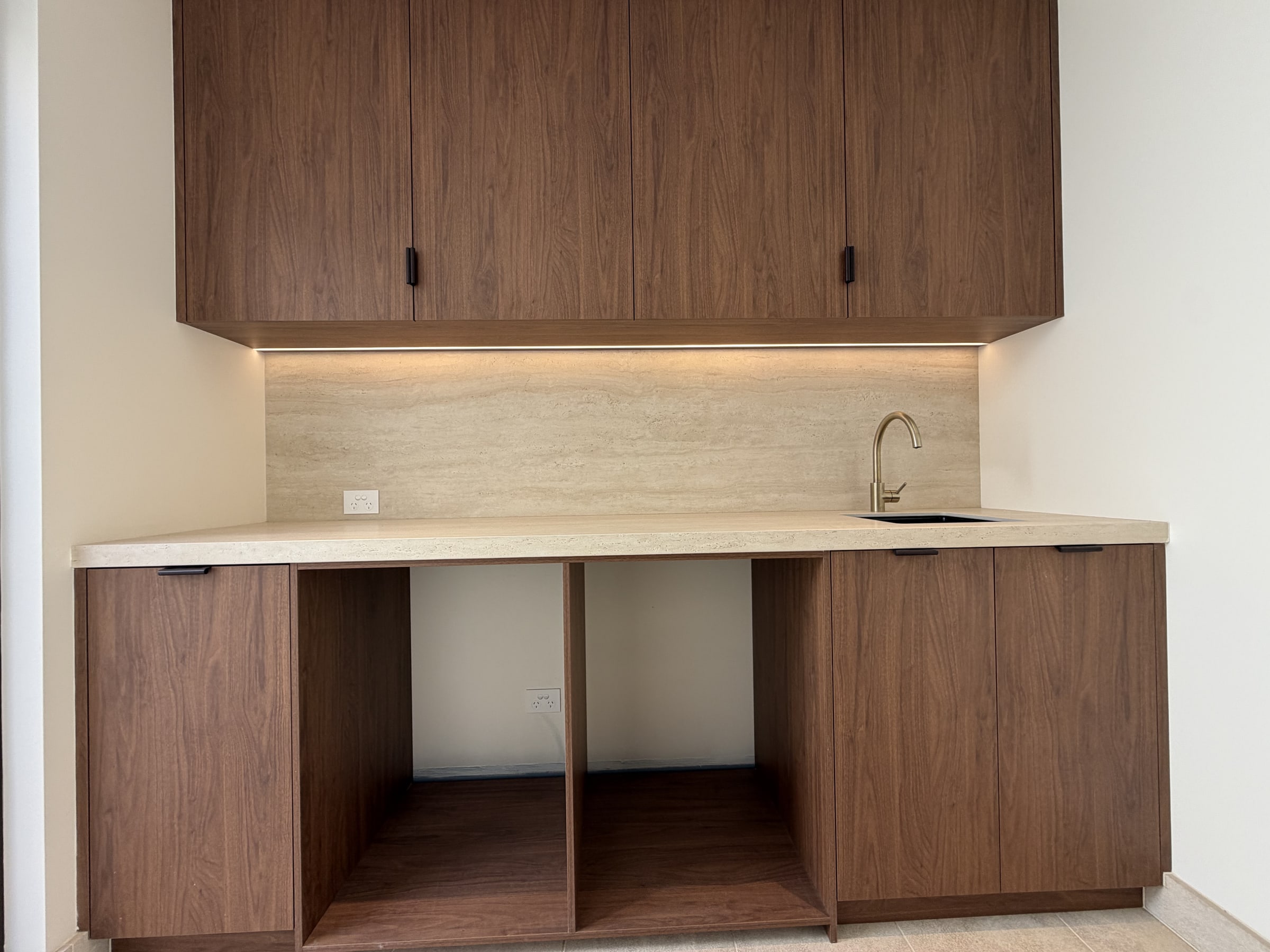 A butler's pantry with a recessed LED strip under the overhead cupboards, a power point on the splashback and a sink