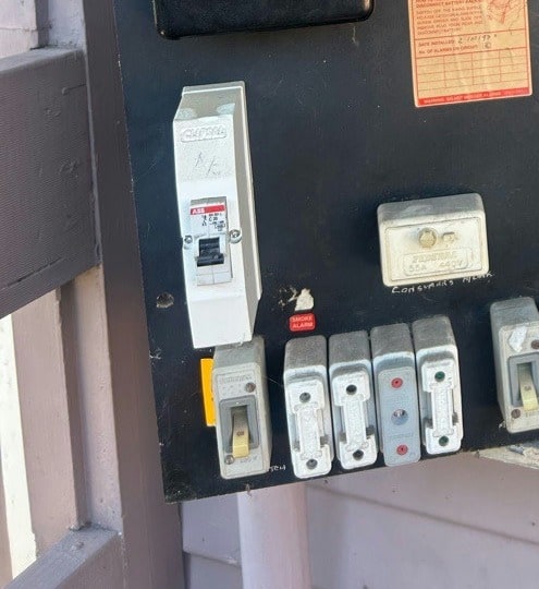 An old panel of ceramic fuses with one newer breaker fitted alongside