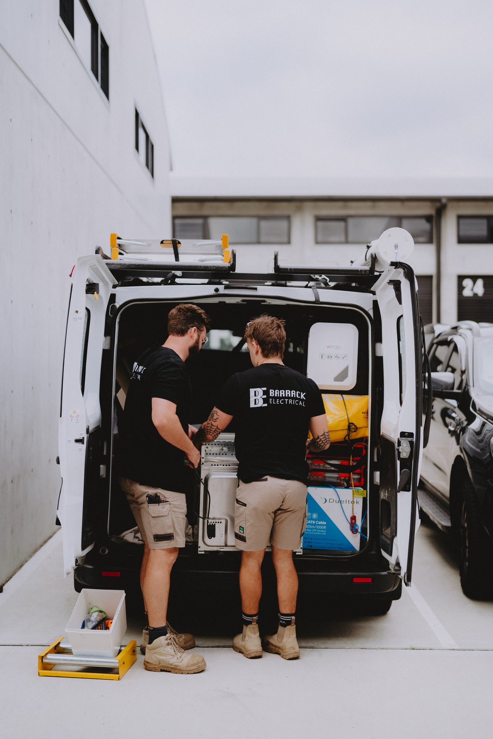 Two Barrack Electrical electricians loading the work van with both rear doors open