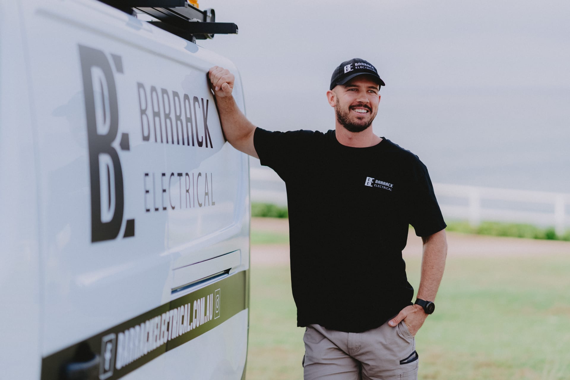 A Barrack Electrical electrician standing with the branded work van on the Newcastle coast