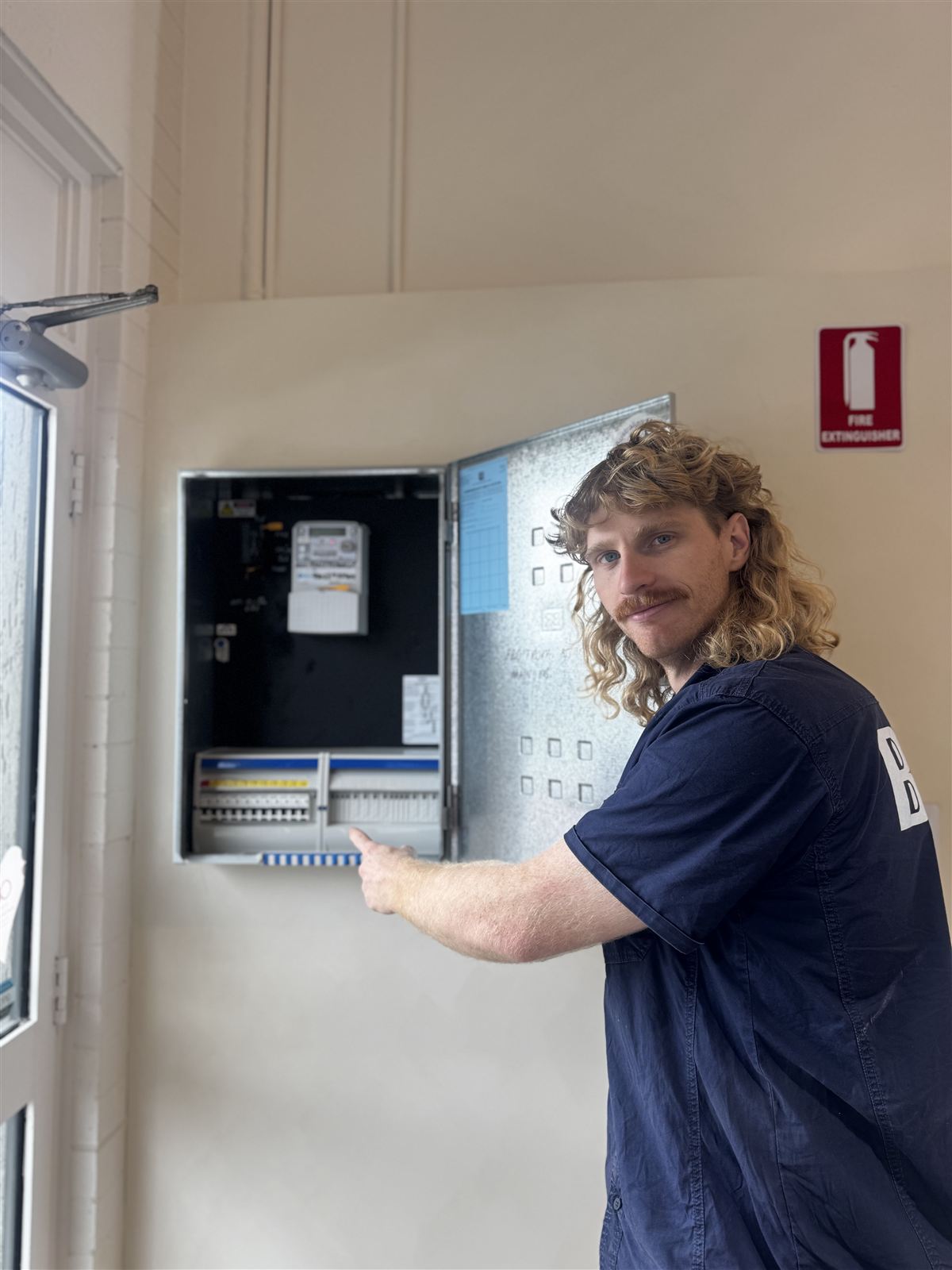 Electrician pointing out circuit breakers on an open commercial switchboard