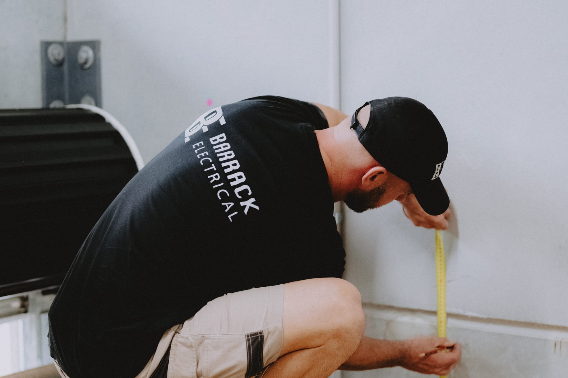 A Barrack Electrical electrician kneeling to measure up before starting work