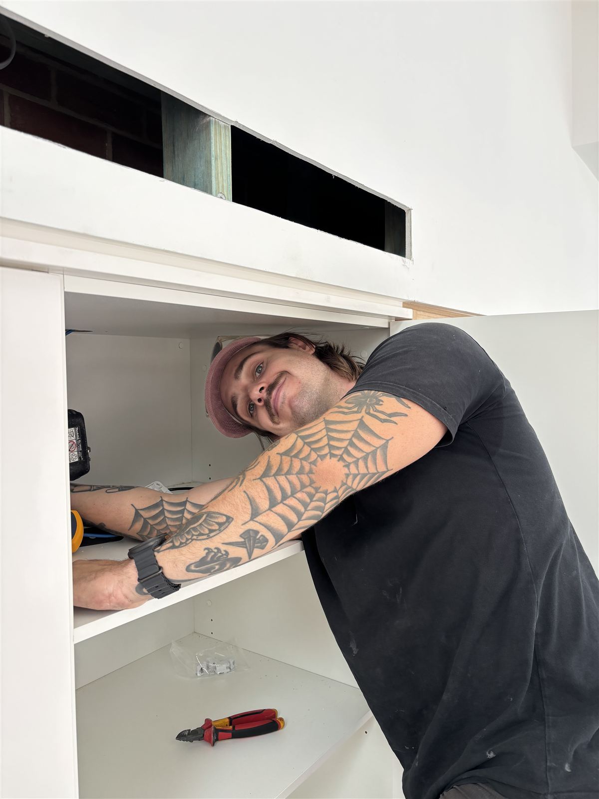 Electrician fitting off wiring inside new kitchen cabinetry