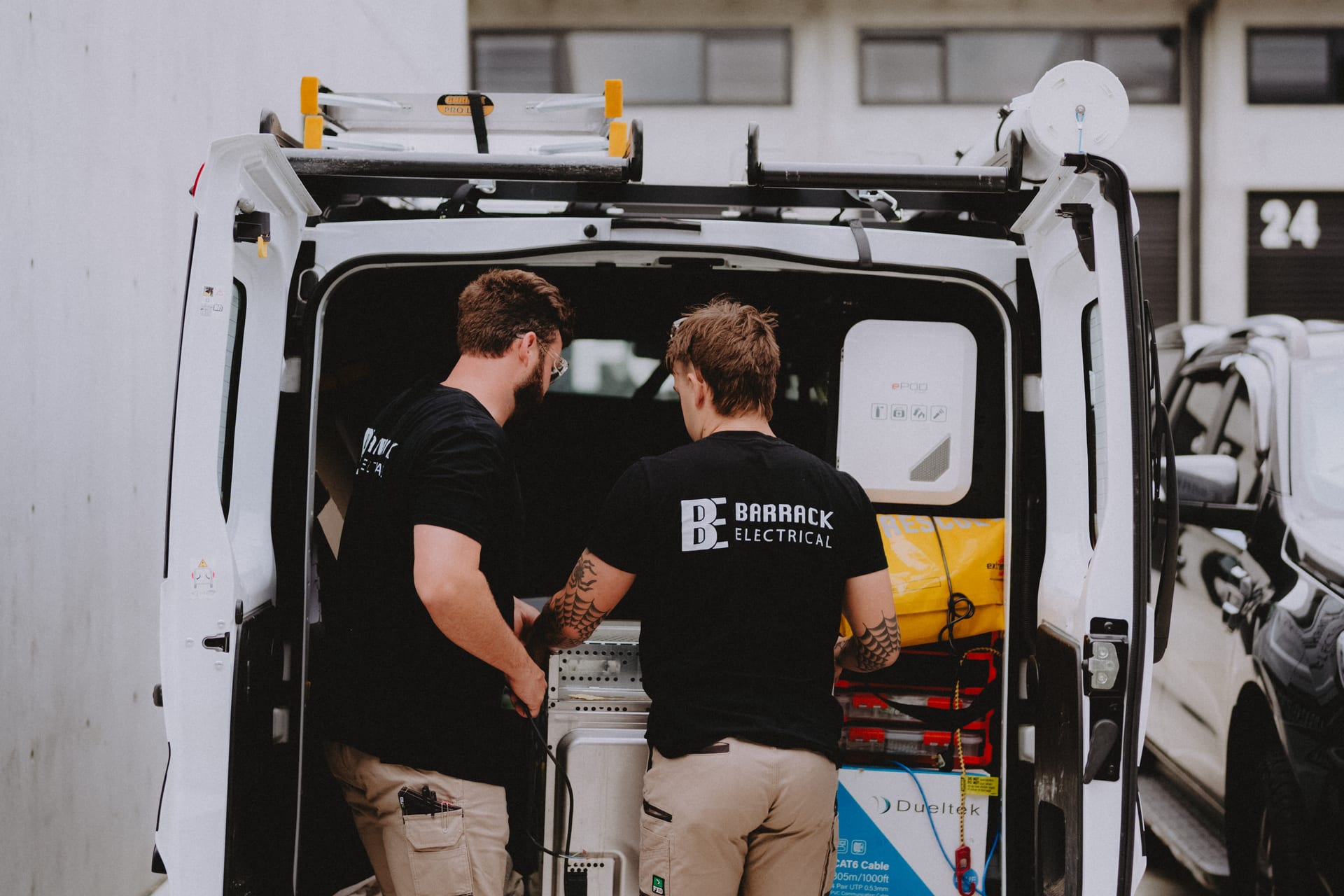 Two Barrack Electrical electricians working out of the open rear doors of the van