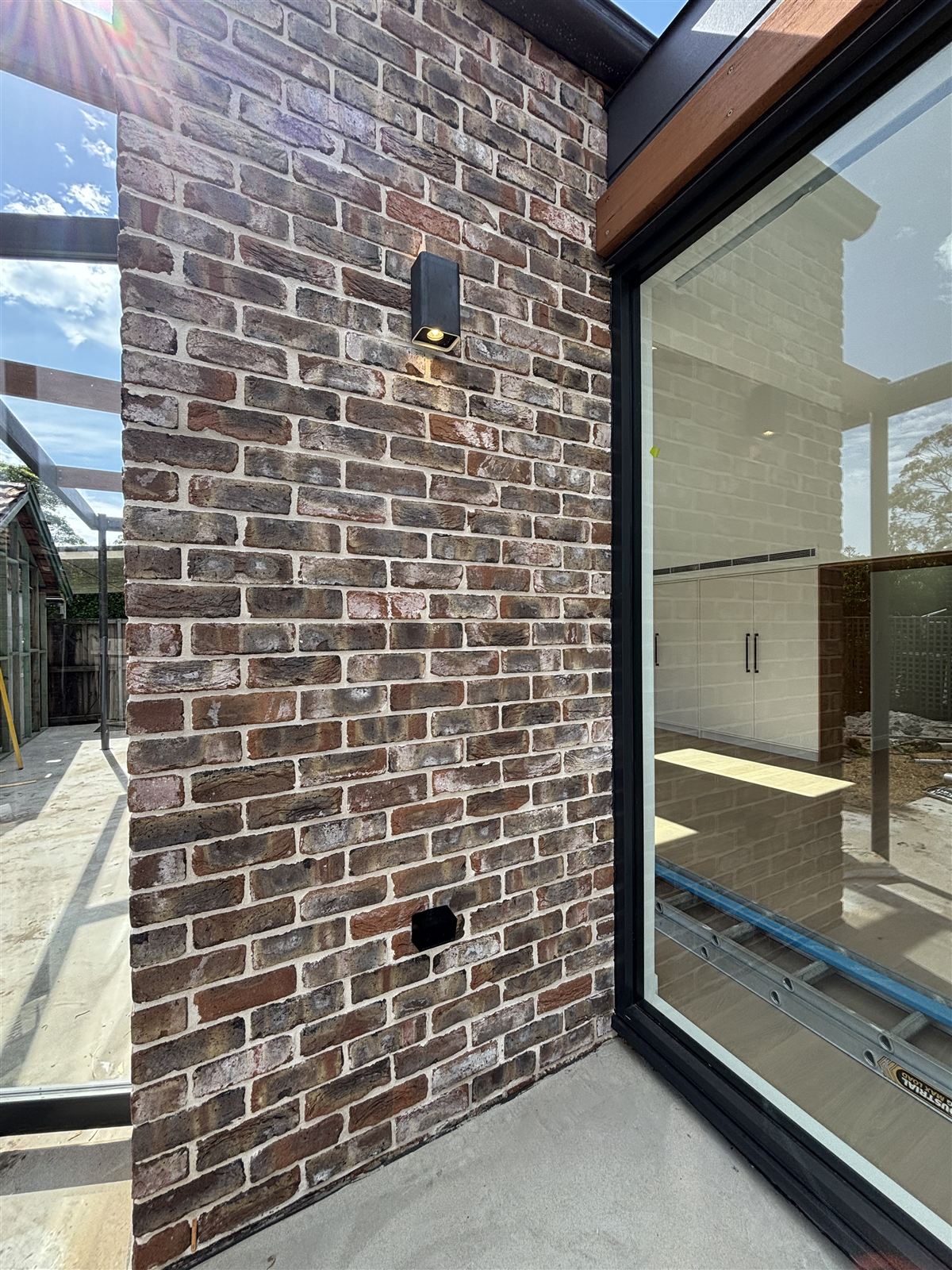 Exterior wall lights on a brick wall beside a large window