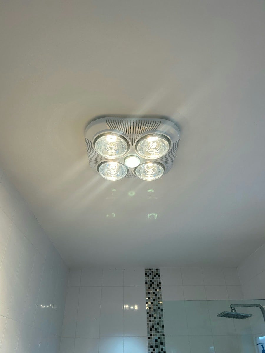 A four-lamp heat unit in a bathroom ceiling with all four lamps lit