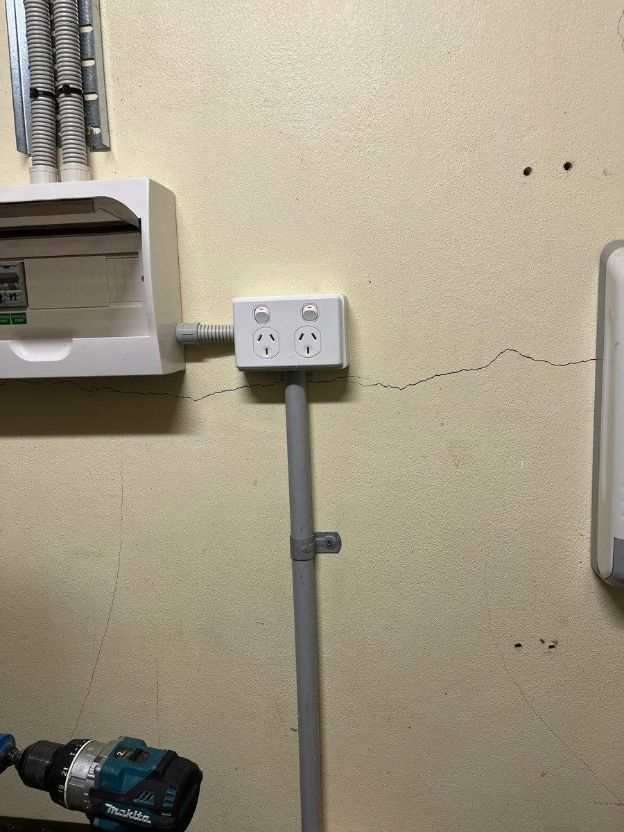 A wall enclosure with a double power point beside it and conduit running down the wall