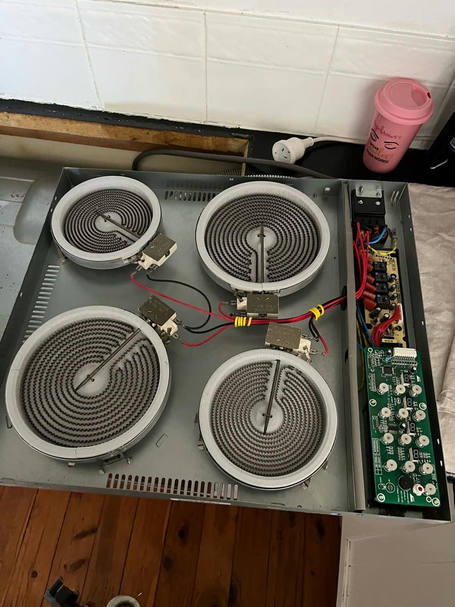 A ceramic cooktop turned over to show the radiant elements, switches and control board