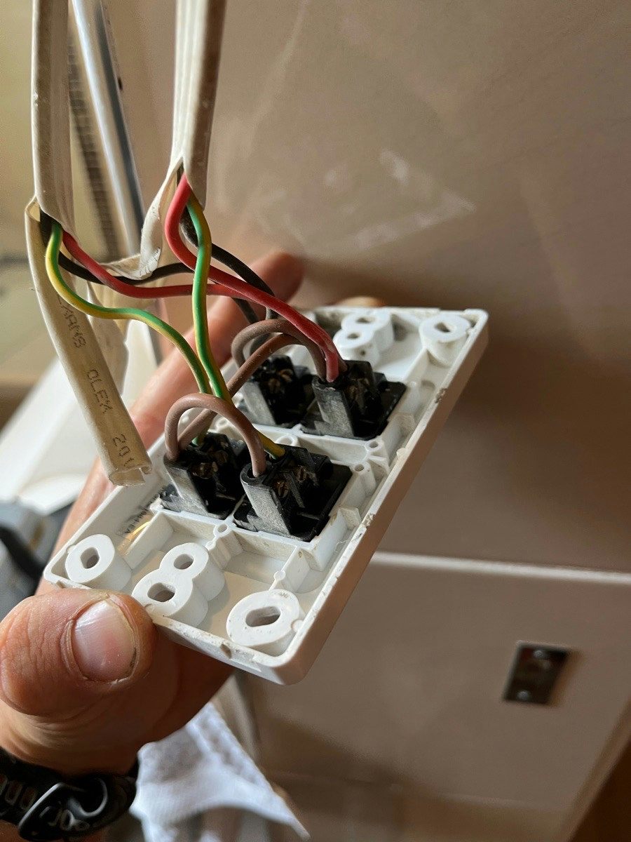 The back of a removed double power point with blackened terminals and old cloth-covered conductors attached