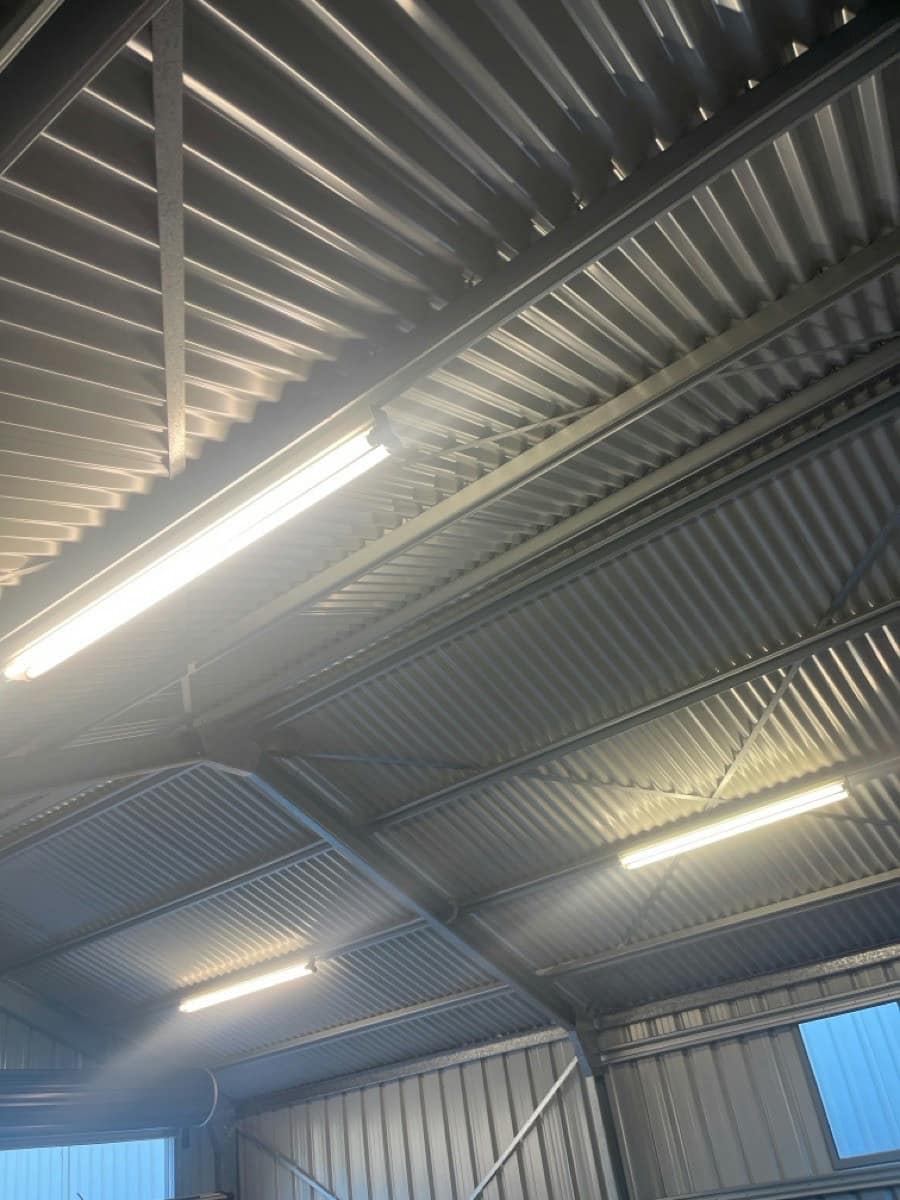 Three LED battens lit along the purlins of a large shed
