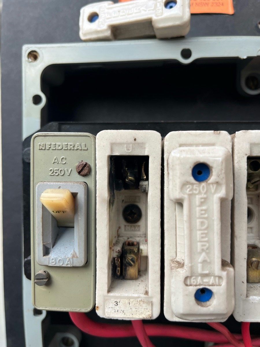 Ceramic fuse carriers in an old board with one carrier withdrawn to show the fuse wire