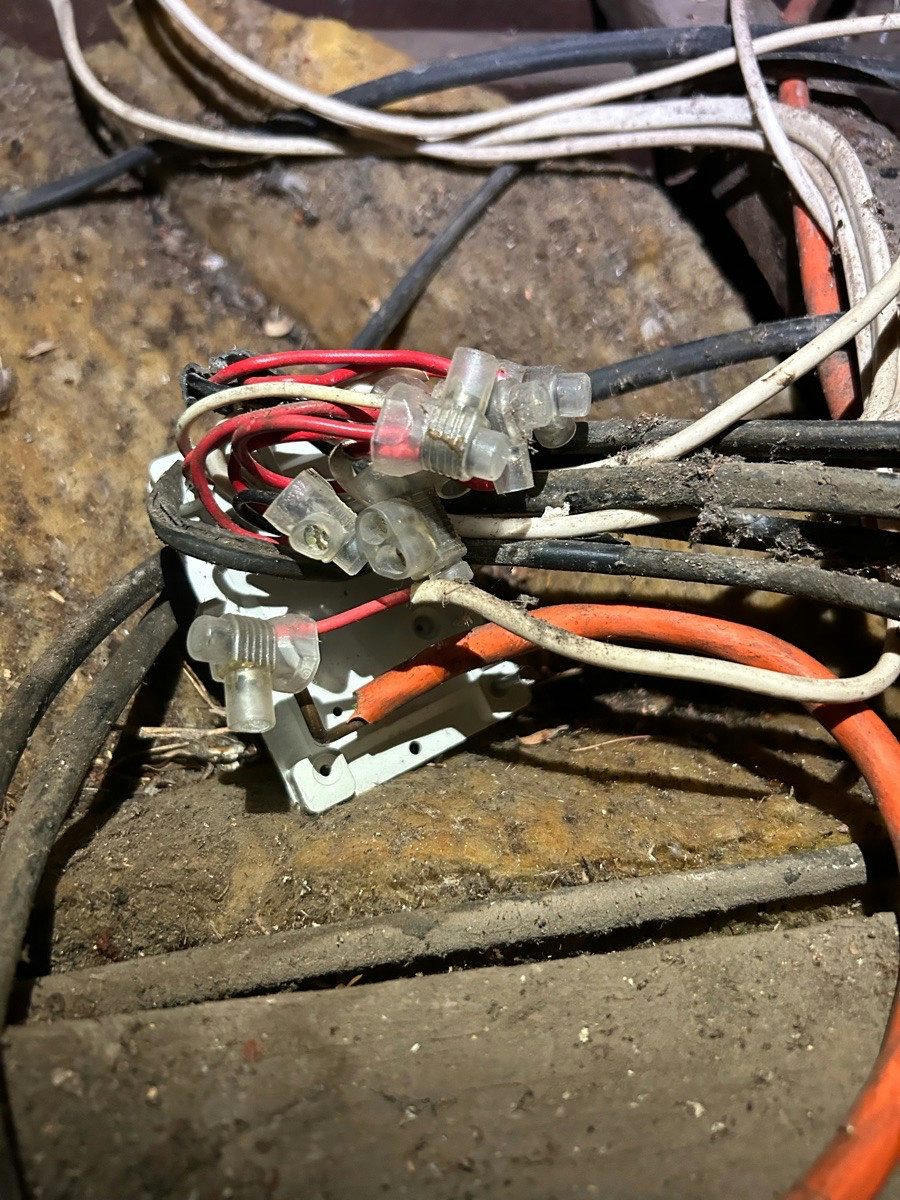 A knot of old cables and made-off joints in an underfloor space