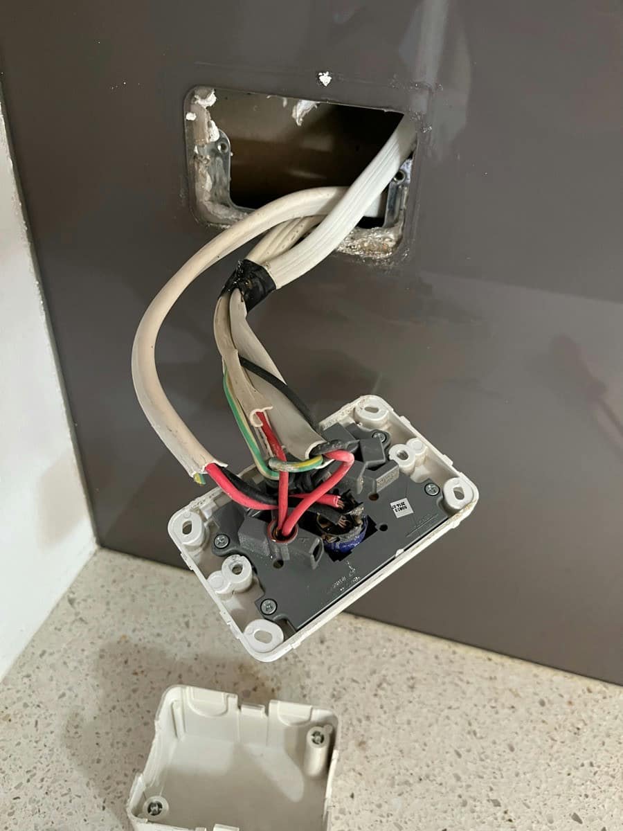 A stove outlet swung down from the wall showing the conductors on its terminal block