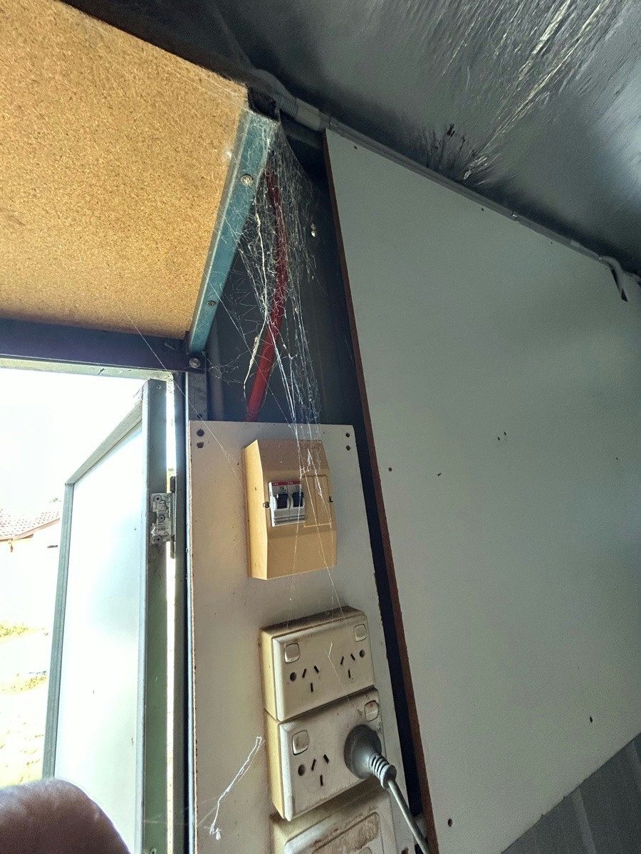 A small board and two double power points on the inside wall of a steel shed