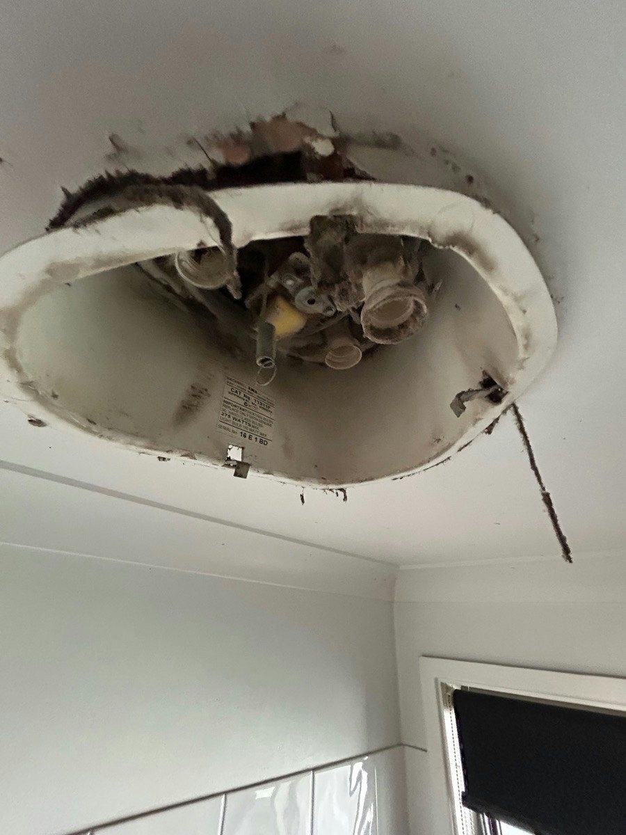 A ceiling fitting with the diffuser removed showing old cabling and soot around the opening