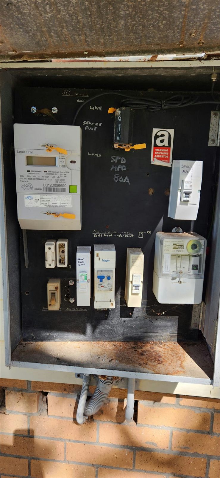 A meter box with heavy rust staining across the base shelf and conduit entering from below