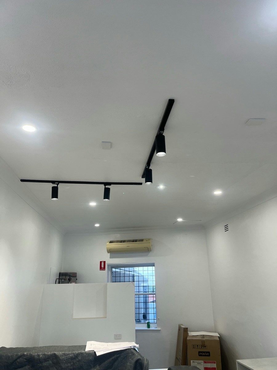 A fitout with downlights and track lighting on, an exit sign on the far wall
