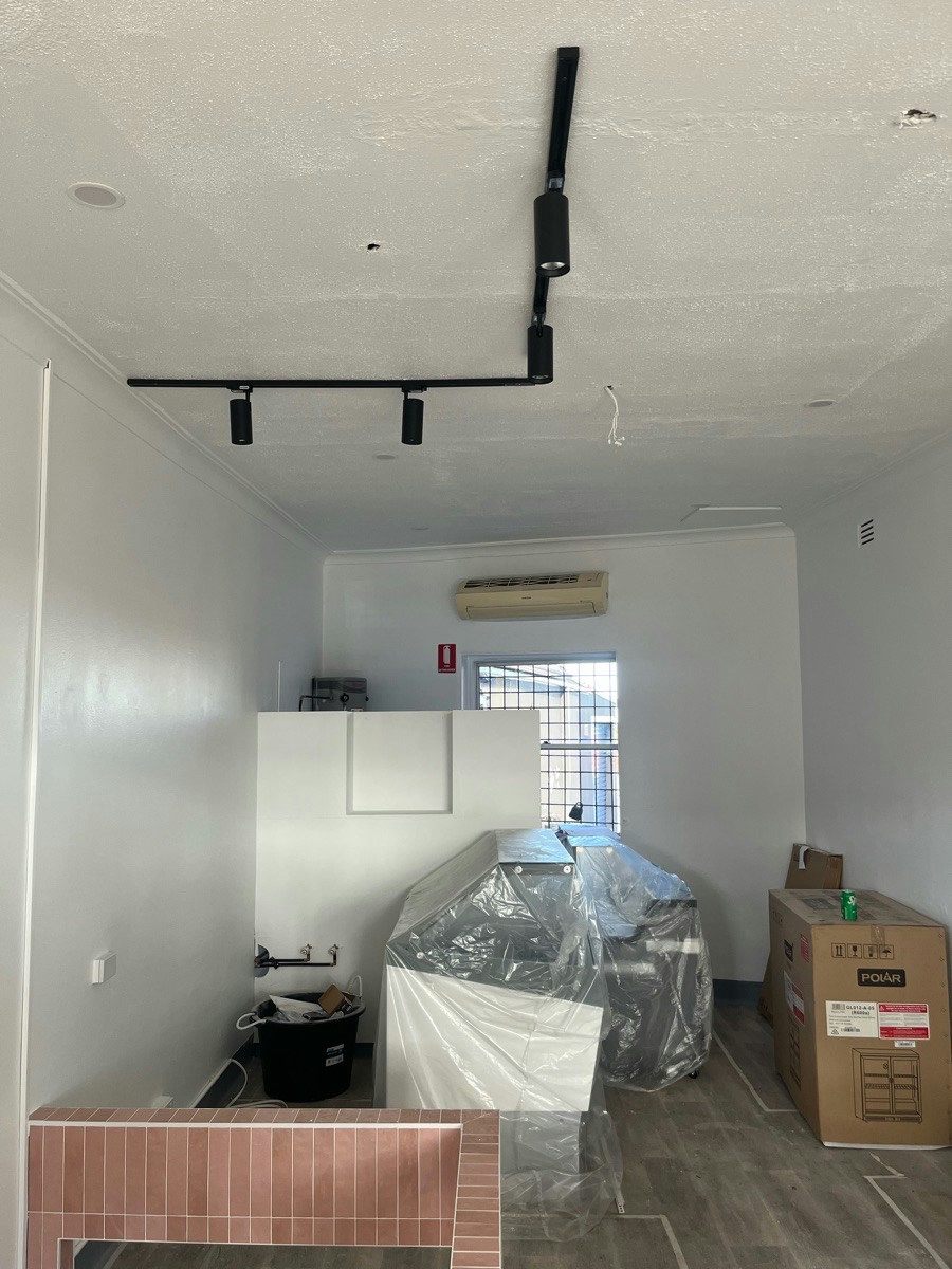 A commercial fitout with track lighting and an exit sign above the rear doorway