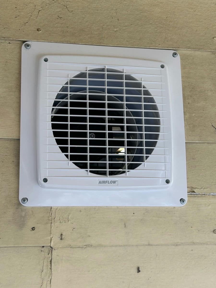 A new square wall exhaust fan fitted to a render and brick wall