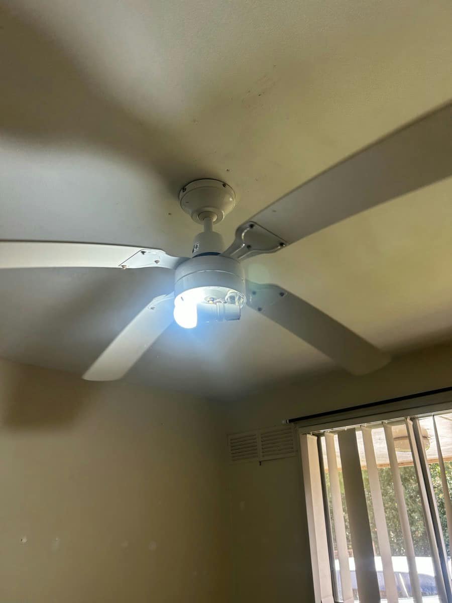 A ceiling fan with its centre light lit