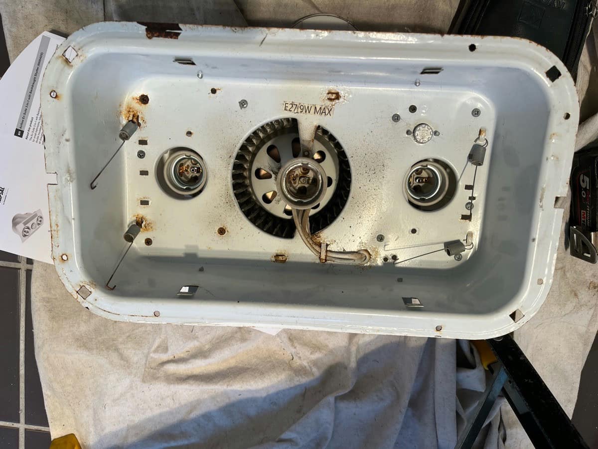 An old three in one unit face down on a drop sheet, the pan rusted and the fan caked with dust