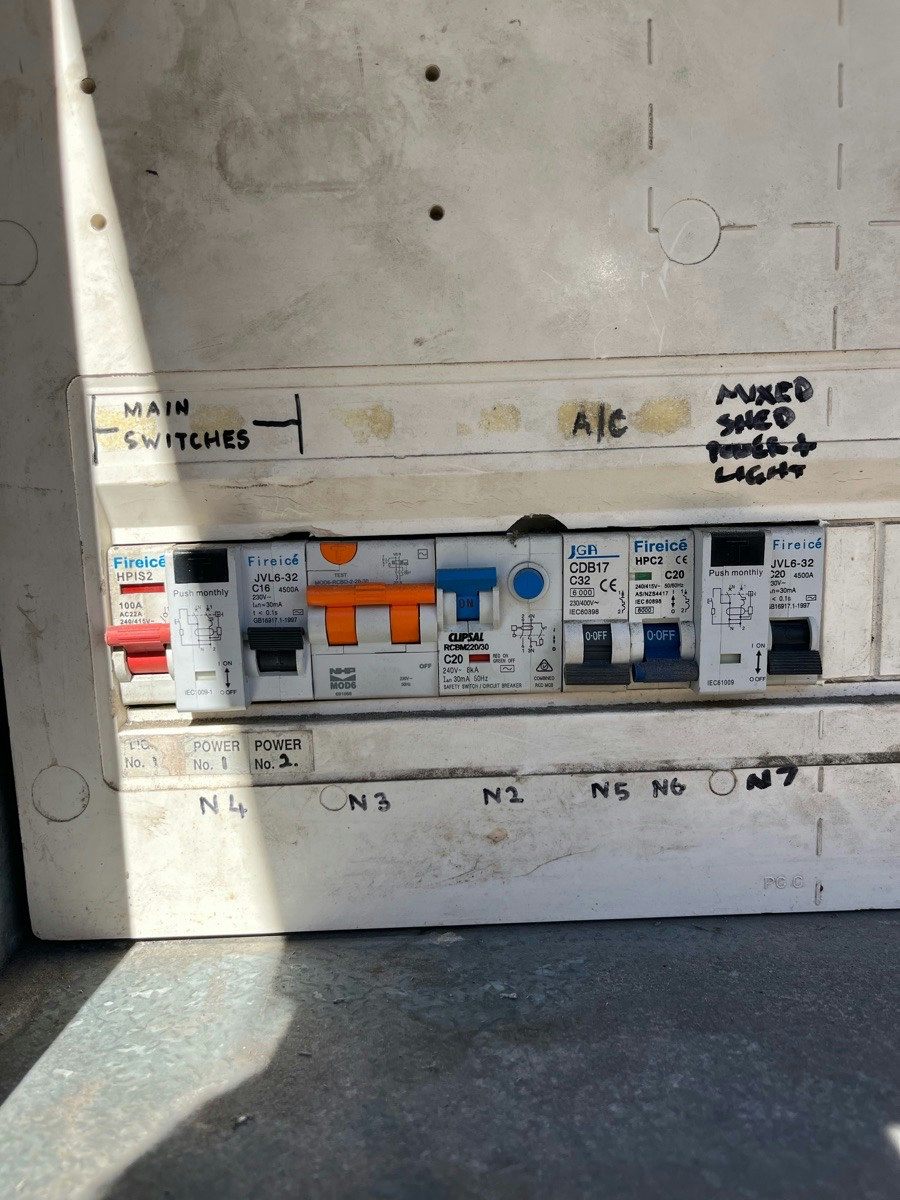 A switchboard with a mixed row of safety switches and older breakers, circuits hand-lettered on the panel