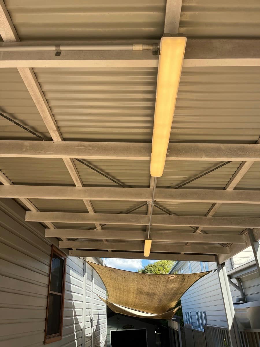 Two batten lights lit under a carport roof