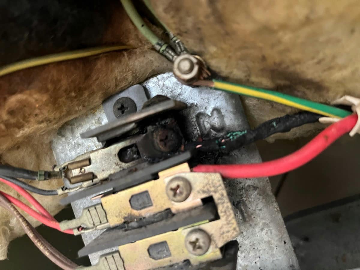 A stove terminal block with the contacts burnt black and the conductors scorched