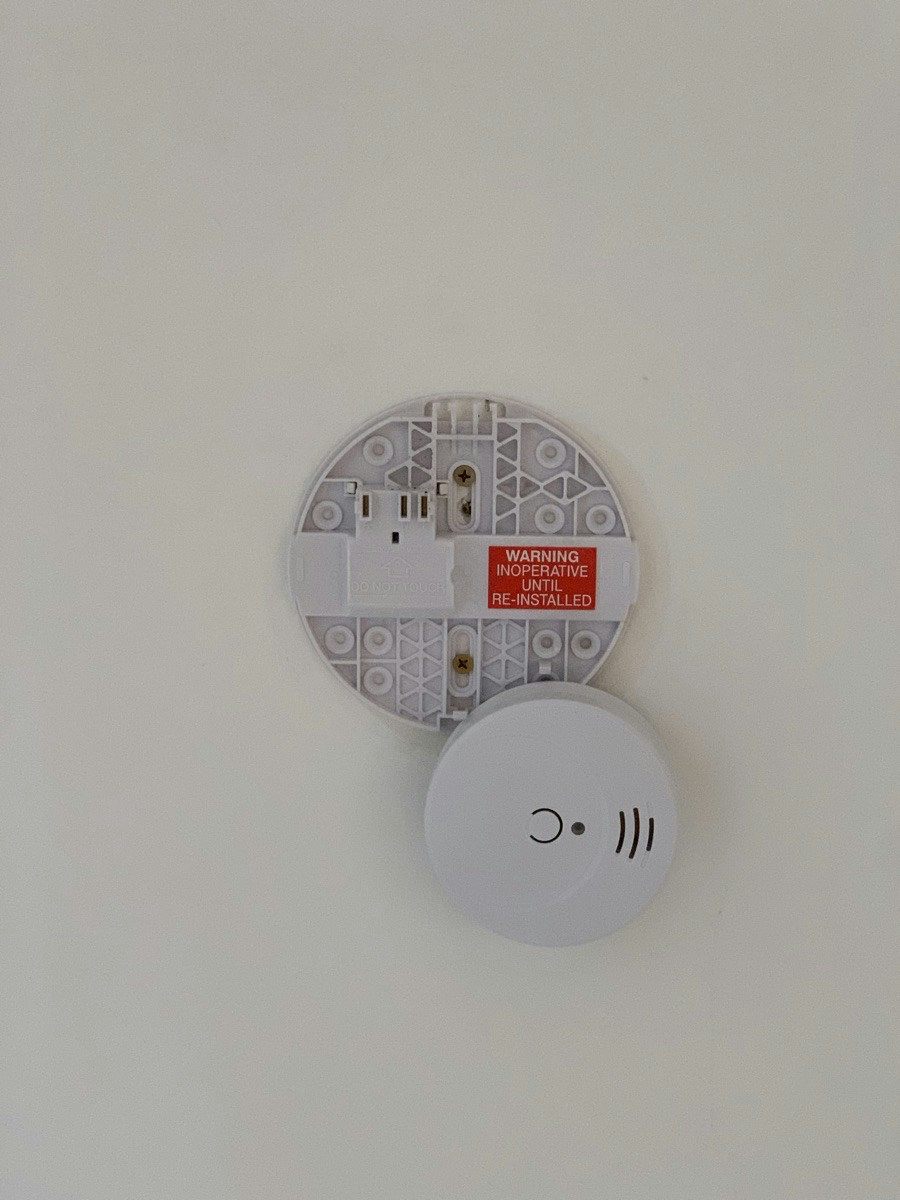 An old smoke alarm base removed and set down beside the new alarm that replaced it