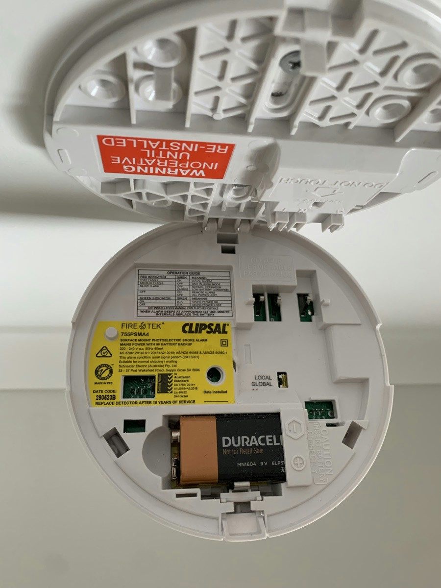 A smoke alarm opened on the ceiling with the nine volt backup battery in place