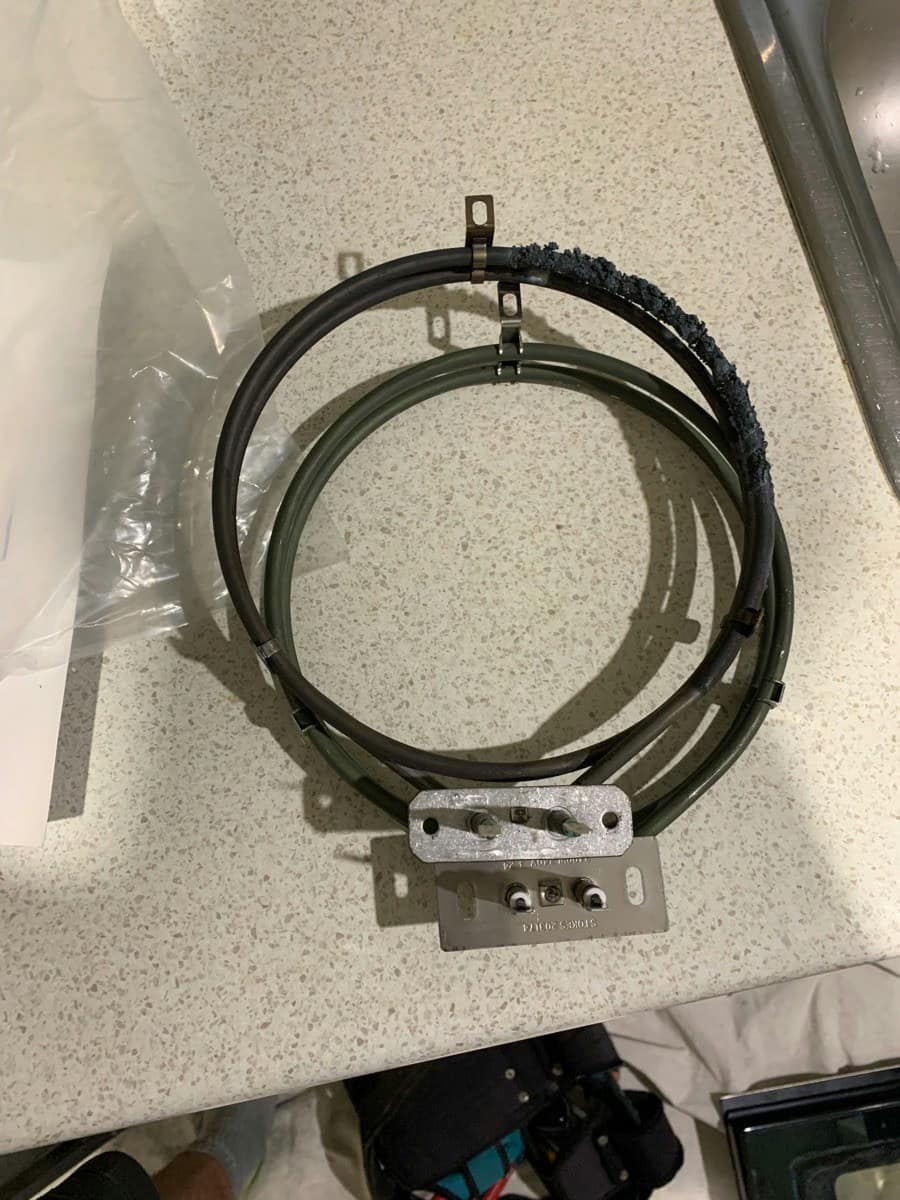 A scaled fan oven element on a benchtop beside its bagged replacement