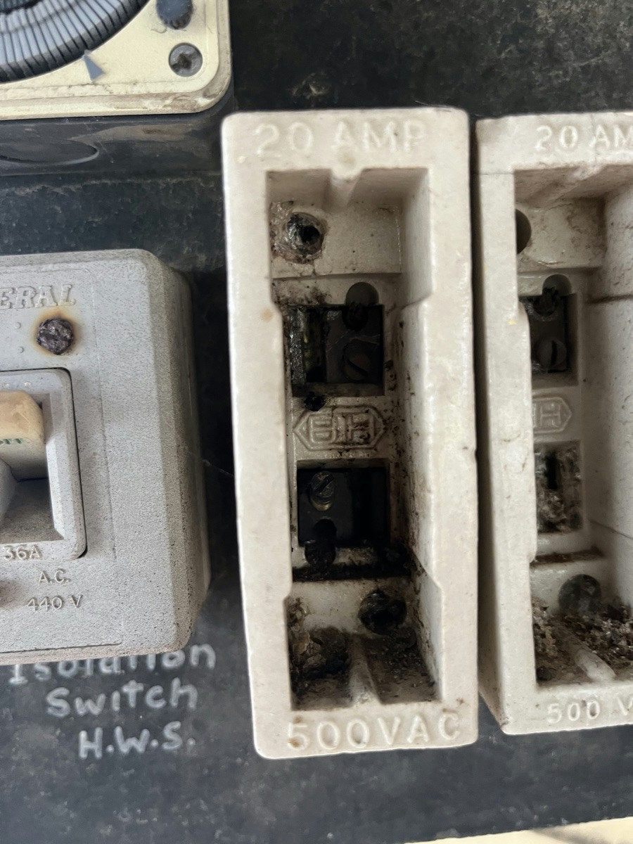 Two twenty amp ceramic fuse holders blackened and pitted from heat inside an old sub-board