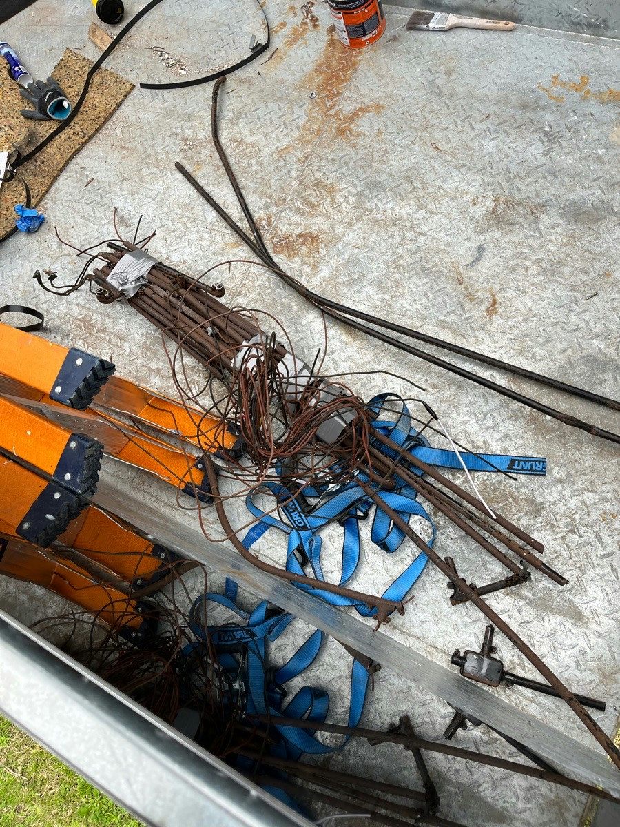 Removed cable coiled on a van tray beside lengths of steel conduit