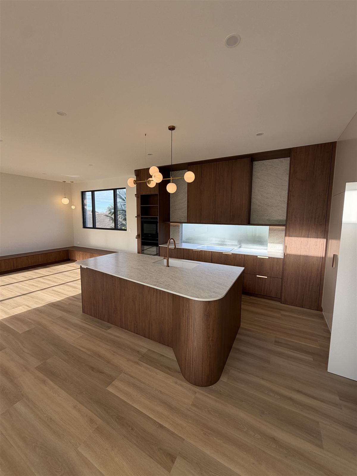 Finished kitchen with LED downlights, globe pendant lights and a curved timber island