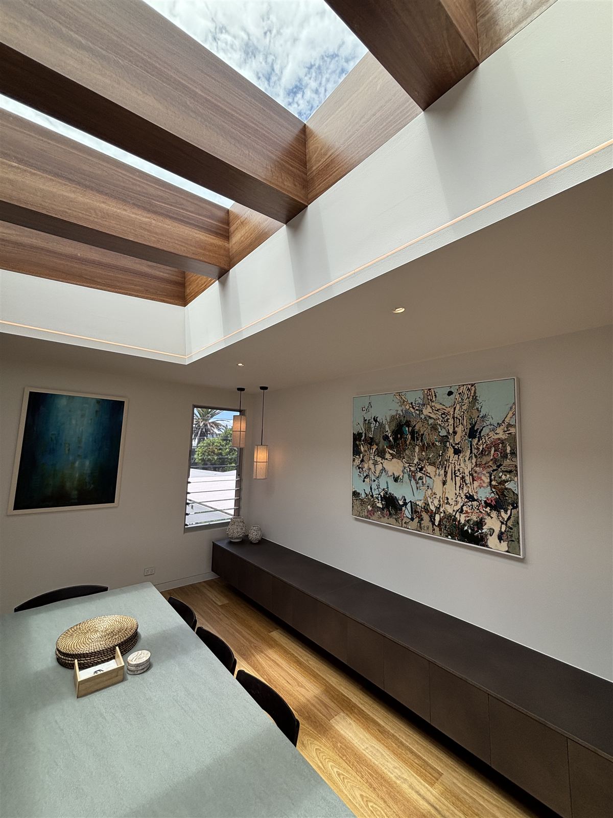 Dining room with LED downlights, LED strip lighting and pendants beneath timber skylights