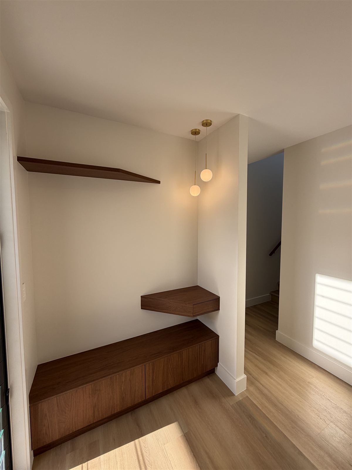 Wall lights above built-in timber shelves in a finished room