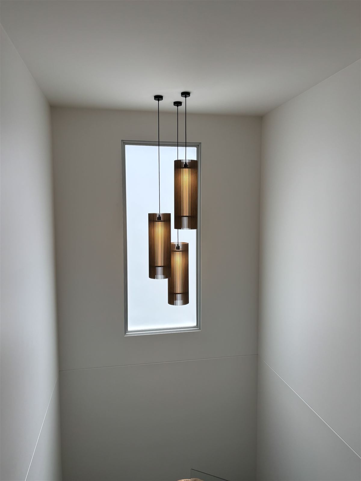 A cluster of pendant lights hung in a stair void