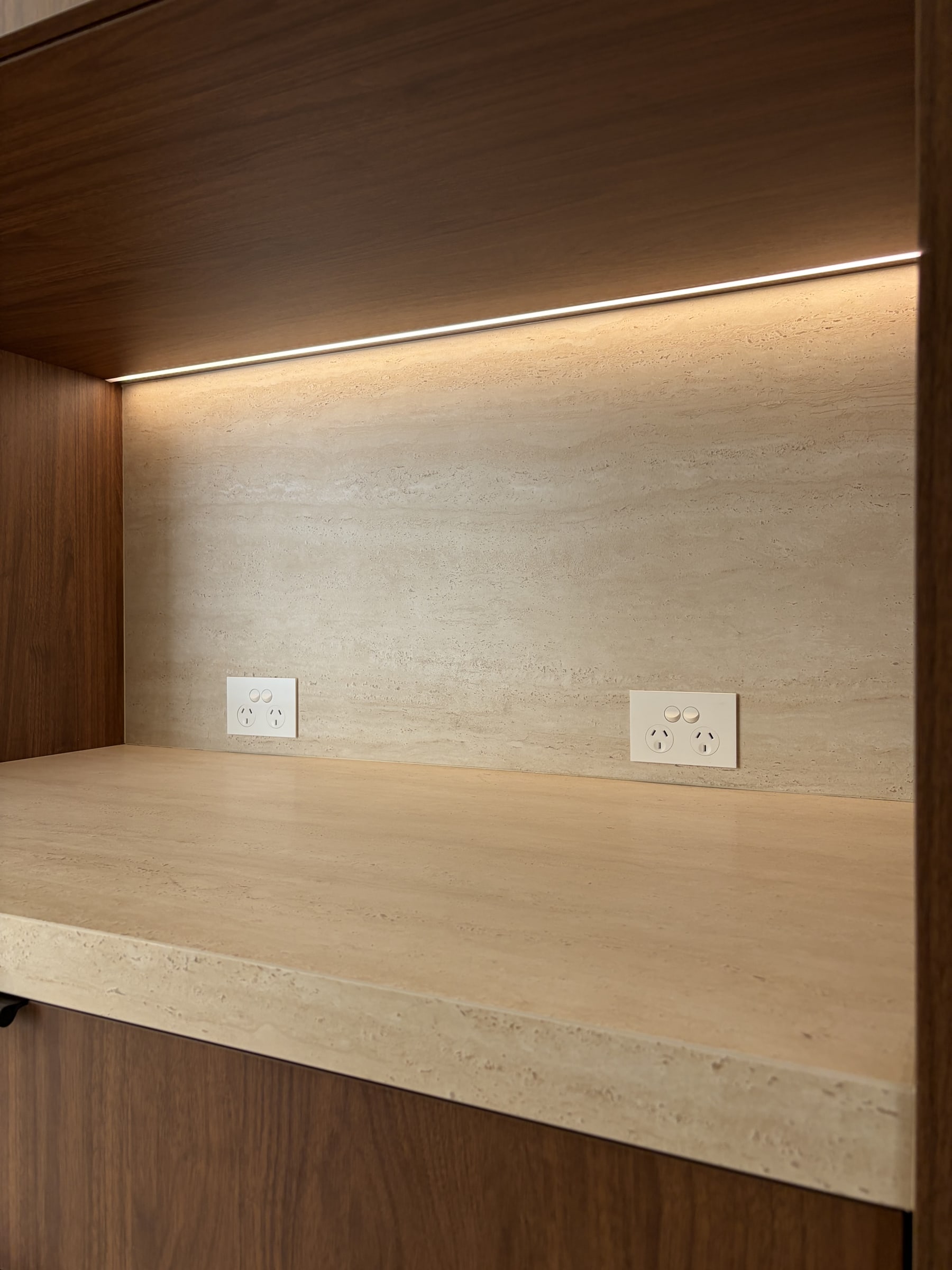 Two double power points set into the stone back of a benchtop niche, with a recessed LED strip lighting it from above