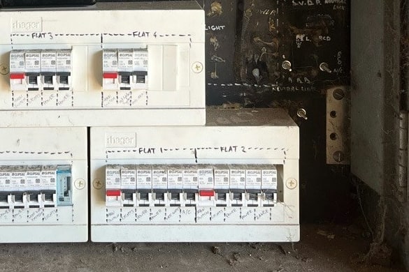 Separate breaker enclosures in a shared meter box, one labelled for each flat