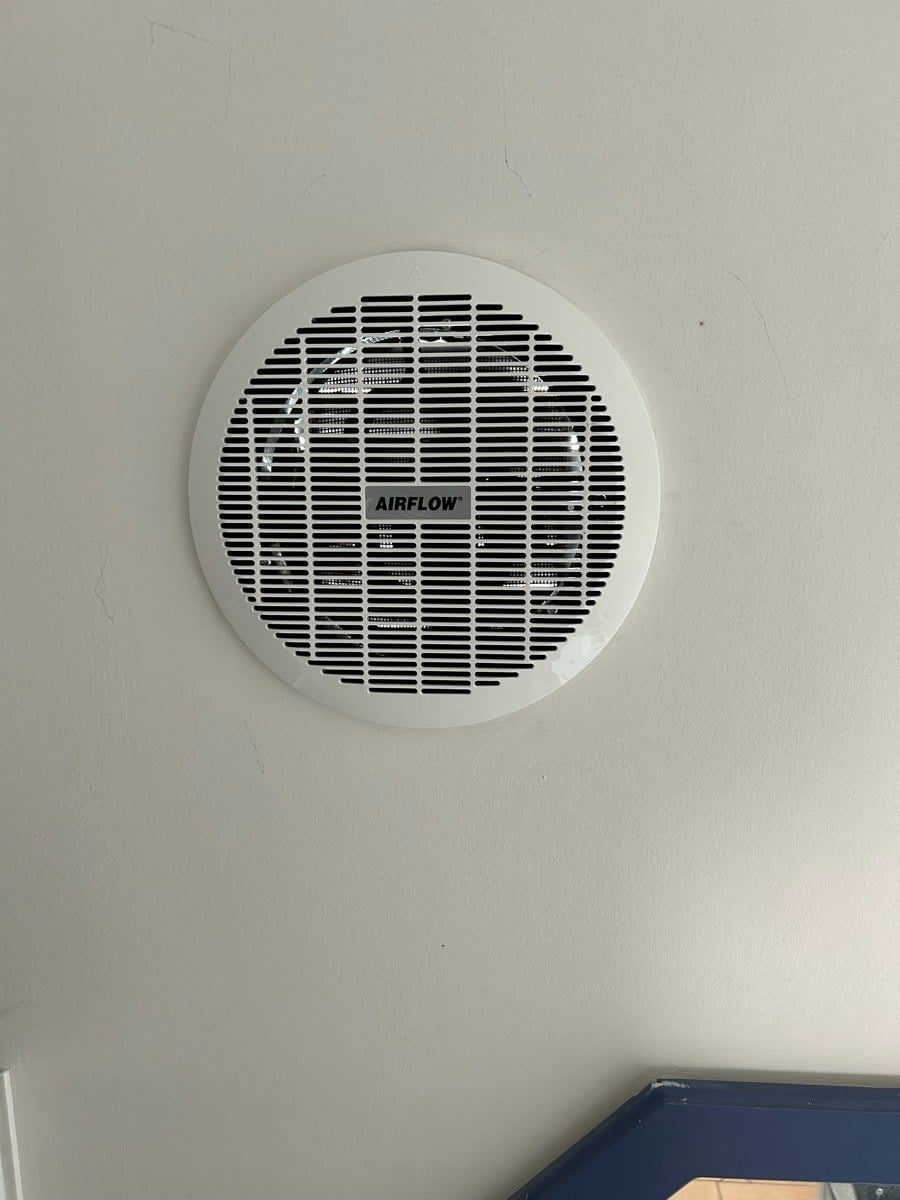 A new round exhaust fan fitted to a wall, its louvred grille clean