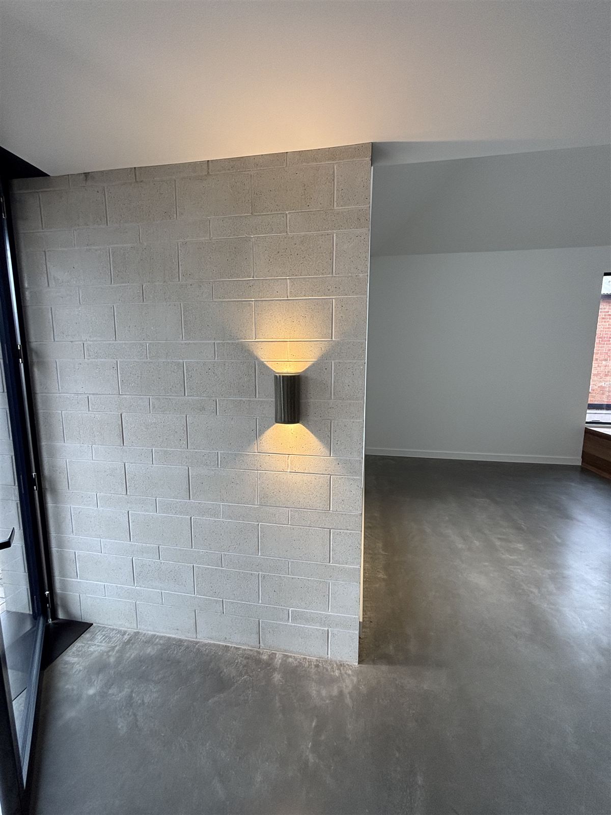 A wall light on a painted block wall above polished concrete