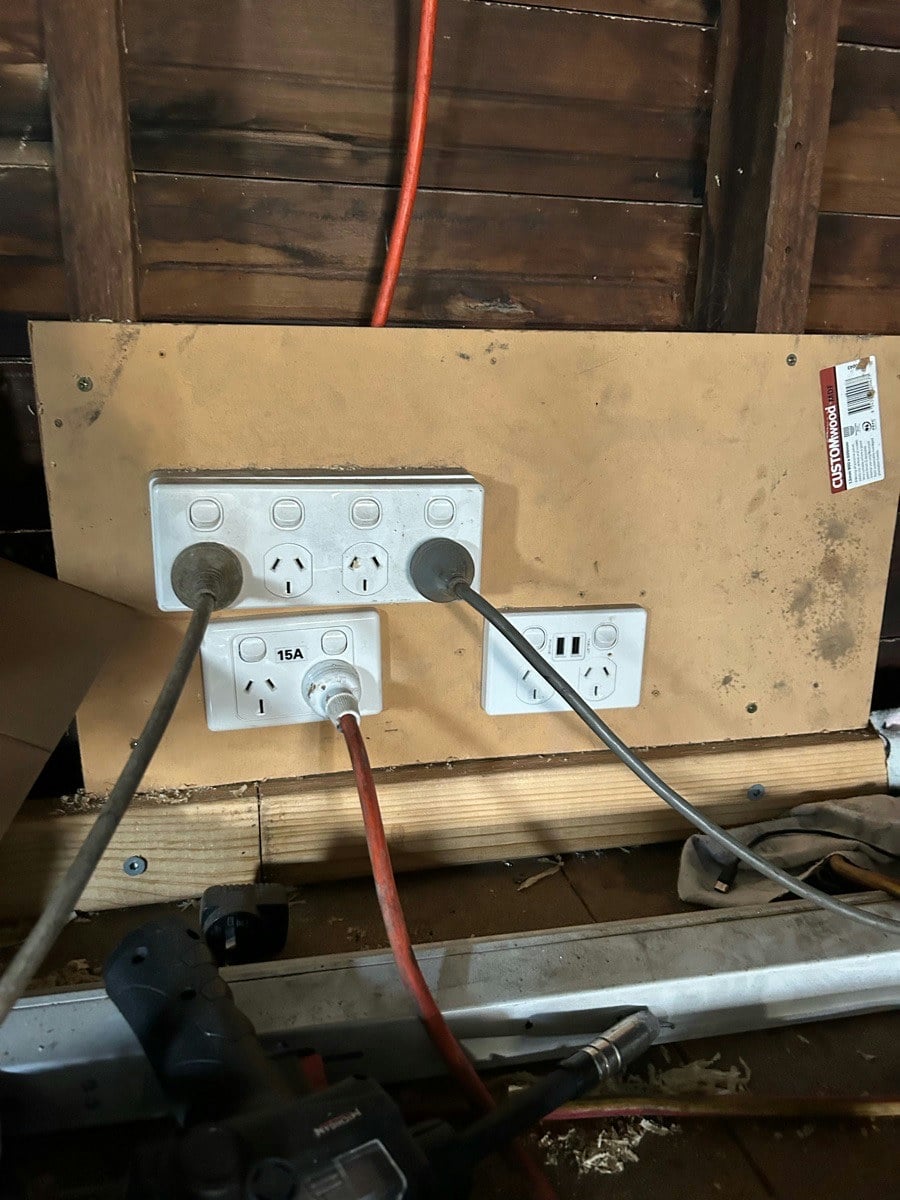 Double power points and a 15 amp outlet mounted on a board above a workbench